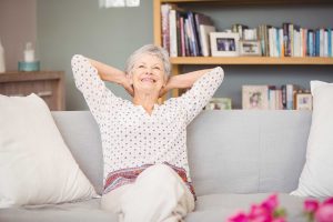 Mujer Senior relajante en sofá después de la construcción de casa de retiro