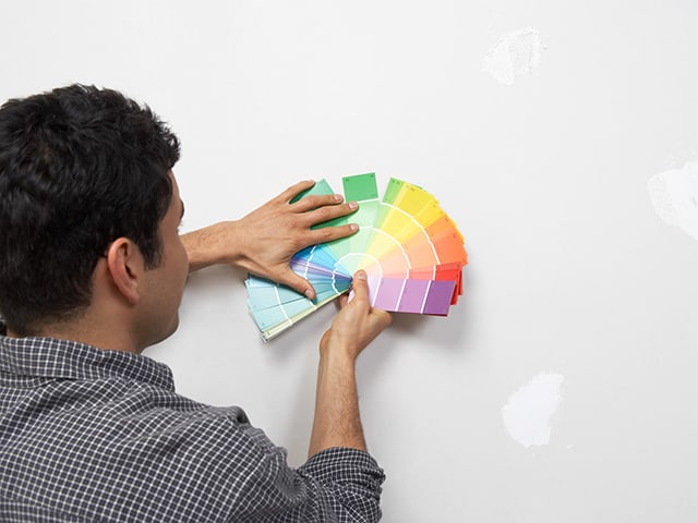 Gerente eligiendo colores de pintura para paredes en proyectos de renovación de hoteles.